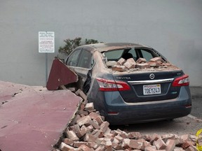 A car damaged by bricks falling during an earthquake is seen next to a downtown building in Napa, California August 24, 2014. The 6.0 earthquake rocked wine county north of San Francisco early Sunday, injuring dozens of people, damaging historical buildings, setting some homes on fire and causing power outages around the picturesque town of Napa.  REUTERS/Stephen Lam