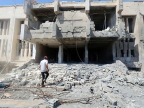 A man inspects damage at the entrance of the National Hospital of al-Tabaqa, caused by what activists said was an airstrike by forces of Syria's President Bashar Al-Assad on the hospital, beside al-Tabqa military base, west of Raqqa August 23, 2014. Al-Tabqa military base, a government-controlled airport surrounded by militants, west of Raqqa city, has been the site of violent clashes between Assad's forces and members of the Islamic State, activists said.  REUTERS/Stringer