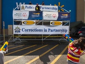 Liam, 4, (left) and Noemi, 9, spray Military Police officer Cpl. Said Omar during Free The Fuzz at the South Edmonton Common Walmart in Edmonton, Alta., on Saturday, Aug. 23, 2014. The fundraiser for Special Olympics Alberta continues through Sunday. Ian Kucerak/Edmonton Sun/ QMI Agency
