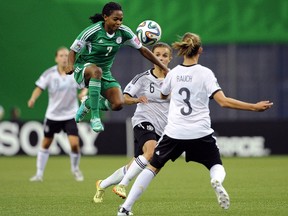Loveth Ayila of Nigeria jumps to move the ball past Lina Magull and Felicitas Rauch of Germany during the FIFA Women's U-20 Final at Olympic Stadium on August 24, 2014 in Montreal, Quebec, Canada. (Richard Wolowicz/Getty Images/AFP)
