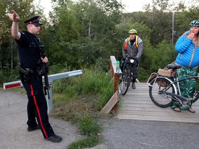 Police direct cyclist out of the ravine near 94 Avenue and 98A Street after a lynx sighting, in Edmonton Alta., on Sunday Aug. 24, 2014. The call originally came in as a cougar spotting. David Bloom/Edmonton Sun/QMI Agency