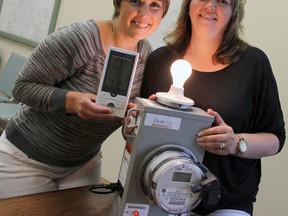 Erin Bourdeau and Ana Couto of Entegrus at the Strathroy office demonstrate how a monitor hooks up to a smart meter to measure energy in dollars or watts to show how much energy used, in this case by a lightbulb.