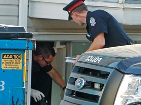 Edmonton Police Service member climbs out a basement window as the police investigated the scene where a body of a male was found in a basement suite of Lorraine Manor at 10727-110 St., in Edmonton, Alta., on Monday, August 25, 2014. Tom Braid/Edmonton Sun