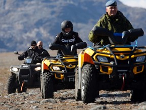 Prime Minister Stephen Harper (2nd R) rides an all terrain vehicle while observing the Operation Nanook military exercise on Baffin Island, Nunavut August 26, 2014. Harper is on the last day of his annual tour of Northern Canada. (REUTERS/Chris Wattie)