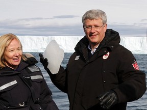 Prime Minister Stephen Harper, right, jokes around with journalists while holding a piece of ice with his wife Laureen aboard the HMCS Kingston on Eclipse Sound, near the arctic community of Pond Inlet, Nunavut on August 24, 2014. (REUTERS/Chris Wattie)
