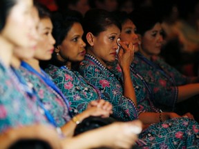 A Malaysia Airlines air stewardess wipes her eyes during a memorial for victims of MH370 and MH17 at Malaysia Airlines headquarters in Kuala Lumpur July 25, 2014. (REUTERS/Olivia Harris)