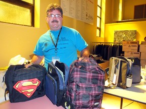 Myles Vanni, executive director of The Inn of the Good Shepherd stands beside a few of the more than 500 backpacks he expects to give out to children in need before school starts. BRENT BOLES / THE OBSERVER / QMI AGENCY