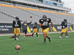 With the new main grandstand and private suites as a backdrop, Ticats defensive back Kyle Miller runs to retrieve a loose ball during Thursday’s workout at Tim Hortons Field in Hamilton. (TICATS.CA/PHOTO)
