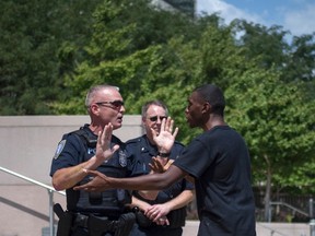 Policemen try to block an activist, who was demanding justice for the shooting death of teen Michael Brown, from advancing past the steps to the Thomas F. Eagleton United States Courthouse in downtown St. Louis, Missouri, August 26, 2014. (REUTERS/Adrees Latif)