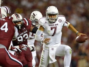 Kenny Hill (right) of the Texas A&M Aggies rolls out under pressure from the South Carolina Gamecocks defence during their game at Williams-Brice Stadium in Columbia, S.C. on Thursday, Aug. 28, 2014. (Grant Halverson/Getty Images/AFP)