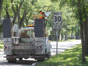 Ryan Laurin with the City of Winnipeg's Traffic Services division removes a cover from a school zone speed limit sign near Dorchester School in Crescentwood on Wed., Aug. 28, 2014. Reduced speed limits in school zones during certain times go in effect Sept. 1. Kevin King/Winnipeg Sun/QMI Agency