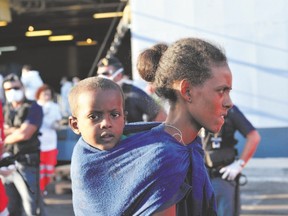 A woman and her child, part of a group of more than 1,370 immigrants, disembark from the Italian military ship San Giusto earlier this week, in the port of Crotone, in southern Italy, following the Mare Nostrum rescue operations at sea. The Italian navy runs the operation to save asylum seekers from drowning on the dangerous voyage, in open boats, from North Africa to Italy. The program began in October 2013. (ALFONSO DI VINCENZO, Agence France Presse)
