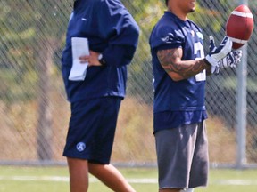 Chad Owens (right), his injured left knee bandaged, watches yesterday’s Argos practice in Mississauga while head coach Scott Milanovich walks behind him. Owens didn’t take part in any drills and probably won’t play on Monday in Hamilton. (Jack Boland, Toronto Sun)