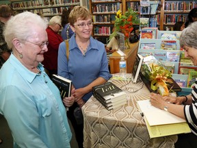 Author and Order of Canada member Frances Itani signs copies of her new novel, Tell, for her cousin, Karen Armstrong, centre, of Madoc, and Muriel Stoliker of Belleville during the book's launch at the Deseronto Public Library Thursday. The book is set entirely in Deseronto, where many of Itani's ancestors lived.