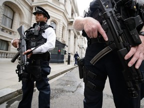 Armed police officers hold guns as they stand in Downing Street, in central London on August 29, 2014.  British Home Secretary Theresa May said on August 29 the country's terror threat risk level was being raised to "severe" due to fears over the situation in Iraq and Syria. AFP PHOTO / LEON NEAL
