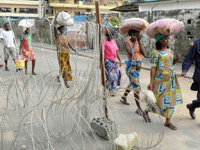 People living outside the Ebola quarantine area of Westpoint walk at a checkpoint while carrying food and essentials for their relatives in quarantine, in Monrovia August 23, 2014. In an attempt to contain the virus, Liberia imposed a quarantine in West Point, a large slum in the capital Monrovia, on August 19. Security forces have been deployed to stop people from entering or leaving the area. (REUTERS/2Tang)