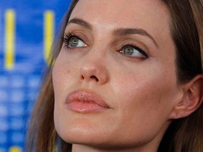 Actress Angelina Jolie, the U.N. refugee agency's special envoy, listens to U.N. High Commissioner for Refugees (UNHCR) Antonio Guterres (not pictured) during a news conference at the Al Zaatri refugee camp, which is hosting Syrians displaced by the conflict, on World Refugee Day, in the Jordanian city of Mafraq, near the border with Syria June 20, 2013. (REUTERS/Muhammad Hamed)