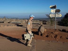 A member of the U.N. Disengagement Observer Force (UNDOF) carries binoculars at an observation post in the Golan Heights that overlooks the Syrian side of the Qunietra crossing August 28, 2014. Syrian jets shelled rebel positions near the border crossing close to the Israeli-occupied Golan Heights that was seized by rebels in some of the heaviest clashes in the strategic area this year, rebels and residents said on Thursday. A U.N. spokeswoman earlier said the organization's peacekeepers could not confirm whether the rebels had seized the crossing, "as fighting is ongoing" at one of its gates. (REUTERS/Ronen Zvulun)