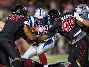 MONTREAL, QC - AUGUST 29: Tyrell Sutton #20 of the Montreal Alouettes is met by Brandon Lang #91 and Jeremiah Green #45 of the Ottawa Redblacks during the CFL game at Percival Molson Stadium on August 29, 2014 in Montreal, Quebec, Canada. The Alouettes defeat the Reblacks 20-10.   Minas Panagiotakis/Getty Images/AFP== FOR NEWSPAPERS, INTERNET, TELCOS & TELEVISION USE ONLY ==