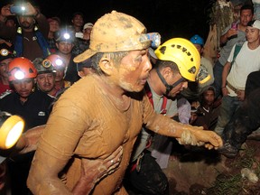 Miners and rescue workers hold a miner (front) covered in mud after he was rescued from a gold mine blocked by a landslide in Bonanza on August 29, 2014. (REUTERS/Oswaldo Rivas)
