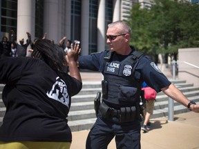 A policeman tries to block an activist, who was demanding justice for the shooting death of teen Michael Brown. (REUTERS/Adrees Latif)