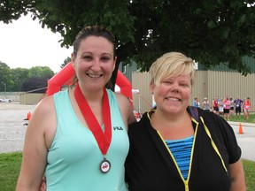 Shelley Wilson, left, of Chatham celebrates her finish in the Maple City Mile with her friend Kelly Tomkins.