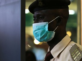 An immigration officer wears a face mask at the Nnamdi Azikiwe International Airport in Abuja August 11, 2014. Nigeria's commercial capital Lagos has 10 confirmed cases of Ebola, up from seven at the last count, and two patients have died, including the Liberian who brought the virus in, the health minister said on Monday. (REUTERS/Afolabi Sotunde)