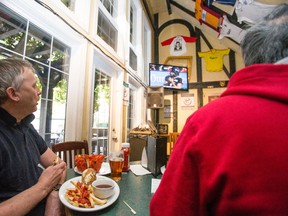 Football fans Waiying Cheng (left) and Jarko Brokki watch the Edmonton Eskimos take on the Calgary Stampeders at Sherlock Holmes Pub in downtown Edmonton on Monday. (IAN KUCERAK/Edmonton Sun)