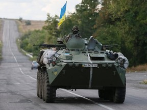 Ukrainian servicemen ride in an armoured vehicle near Debaltseve, Donetsk region, August 29, 2014. Ukraine wants supplies of weapons but does not expect NATO to send soldiers to help it fight Russian troops in its eastern provinces, Kiev's ambassador to NATO said on Friday.  REUTERS/Gleb Garanich