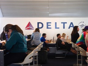 Passengers sit in stations equipped with iPads ahead of their flights at a Delta terminal in LaGuardia Airport in New York June 22, 2014. Picture taken June 22, 2014. (REUTERS/Adrees Latif)