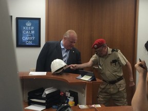 Jim McMillan, of the Rob Ford Rangers, hands Mayor Rob Ford discarded TTC construction helmets he found thrown away downtown at City Hall on Thursday, August 7, 2014. (Don Peat/Toronto Sun)