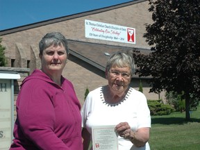 Diana Player, left, and Jean MacArthur hold an invitation to a 150th anniversary celebration in front of St. Thomas Christian Church (Disciples of Christ) on Wellington St. The church traces its roots back to 1864 and recently added a banner to the church building (pictured in back). Player is chairwoman of the 150th anniversary committee and MacArthur is a church historian. A service of celebration is being planned for 2 p.m. on Sunday, Sept. 14. (Ben Forrest, Times-Journal)