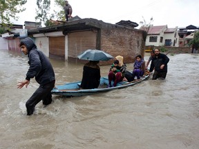 Kashmiri women and a child are transported in a boat through a flooded road to a safer place during incessant rains in Srinagar on September 4, 2014. (REUTERS/Danish Ismail)