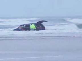 In this still image captured from video, rescuers pull three children from a minivan tossing in the surf at Daytona Beach, Florida March 4, 2014. (REUTERS/Simon Besner)