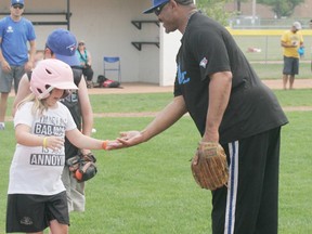 Ex-Toronto Blue Jay, Lloyd Moseby, offers a variation of a high-five to a young lady as she makes her way to first base during the Challenger Baseball Program, held in the Grove on Aug. 15 at Henry Singer Park. - Gord Montgomery, Reporter/Examiner