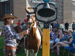 Kim Secco holds the reins as Doris, a horse from the Texas Longhorn Ranch near Strathroy, pulls an apple off a rope attached to a bell to ring in the start of the Western Fair in London Friday. (CRAIG GLOVER, The London Free Press)