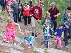 Jim Moodie/The Sudbury Star
Sophie Loiselle and Effie Godwin, foreground, take a shortcut on the Story Trail, while other hike participants, including Laura Gregorini, right, with children Alessandro, Chiara and Tommaso, follow the beaten path. Children's author Frank Glew and teenaged grandson Samuel, clad in hoodie and ball cap, are visible behind the Gregorini clan.