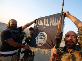 Iraqi Shiite militia fighters hold the Islamic State flag as they celebrate after breaking the siege of Amerli by Islamic State militants, September 1, 2014.  REUTERS/Youssef Boudlal