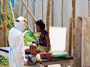 A health worker, wearing head-to-toe protective gear, offers water to a woman with Ebola, at a treatment centre for infected persons, as a young boy stands nearby in Kenema Government Hospital, in Kenema, Eastern Province, Sierra Leone.

(UNICEF/Reuters)