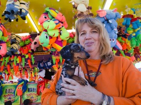 Linda Collier of Tiny Paws Dog Rescue Canada hopes that people will take home a real animal, as well as the the stuffed kind,  from the Western Fair in London Ontario on Sunday, September 7, 2014. She holds one of the dogs available, a dachshund terrier named "Blue" who was rescued from a garbage dumpster. (DEREK RUTTAN, The London Free Press)