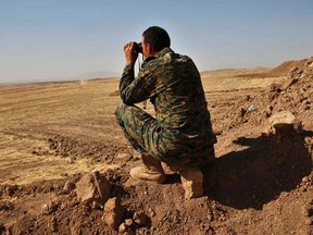 A Kurdish peshmerga fighter uses a pair of binoculars to look at tanks shelling Islamic State positions at the Khazir front line leading to Mosul September 7, 2014.  REUTERS/Ahmed Jadallah