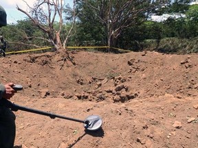Handout picture released by the Nicaraguan presidency press office showing a Nicaraguan soldier checking the site where an alleged meteorite struck on September 7, 2014 in Managua.  AFP PHOTO / PRESIDENCIA - EL 19 DIGITAL - GERMAN MIRANDA