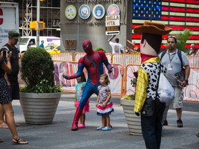 A person dressed in a Spider-Man costume stands with children in the Times Square region of New York, August 11, 2014.  REUTERS/Lucas Jackson
