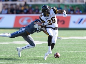 Ticats running back Mossis Madu (right) loses the ball while being tackled by the Alouettes’ Winston Venable during CFL action Sunday at Molson Stadium in Montreal. (Getty Images)
