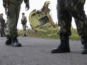 Armed pro-Russian separatists stand guard as monitors from the Organization for Security and Cooperation in Europe (OSCE) and members of a Malaysian air crash investigation team inspect the crash site of Malaysia Airlines Flight MH17, near the village of Hrabove (Grabovo), Donetsk region in this July 22, 2014 file photo.   REUTERS/Maxim Zmeyev/Files