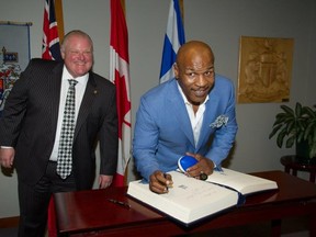 Mike Tyson signs the guest book in the mayor's office as Mayor Rob Ford looks on Tuesday, Sept. 9, 2014. (Photo courtesy of the City of Toronto)