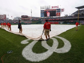Members of the grounds crew hold a tarp covering the playing field during a rain delay prior to the game between the Giants and Nationals in August. Nationals Park will host the 2015 Winter Classic as the Capitals take on the Blackhawks on Jan. 1. (Geoff Burke/USA TODAY Sports)