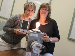 Erin Bourdeau and Ana Couto of Entegrus at the Strathroy office August 21, demonstrating how a monitor hooks up to a smart meter to measure energy in dollars or watts to show how much energy used, in this case by a lightbulb.