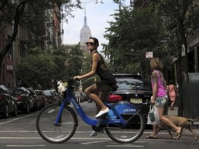 The Empire State Building is seen in the distance as a woman rides a Citibike in the Soho neighbourhood of New York July 27, 2013. Reuters/Gary Hershorn