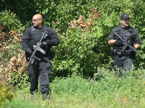 Armed police officers search the bush lot behind Charles H. Hulse school after a student repoprted seeing a man with a silver handgun.DOUG HEMPSTEAD/Ottawa Sun